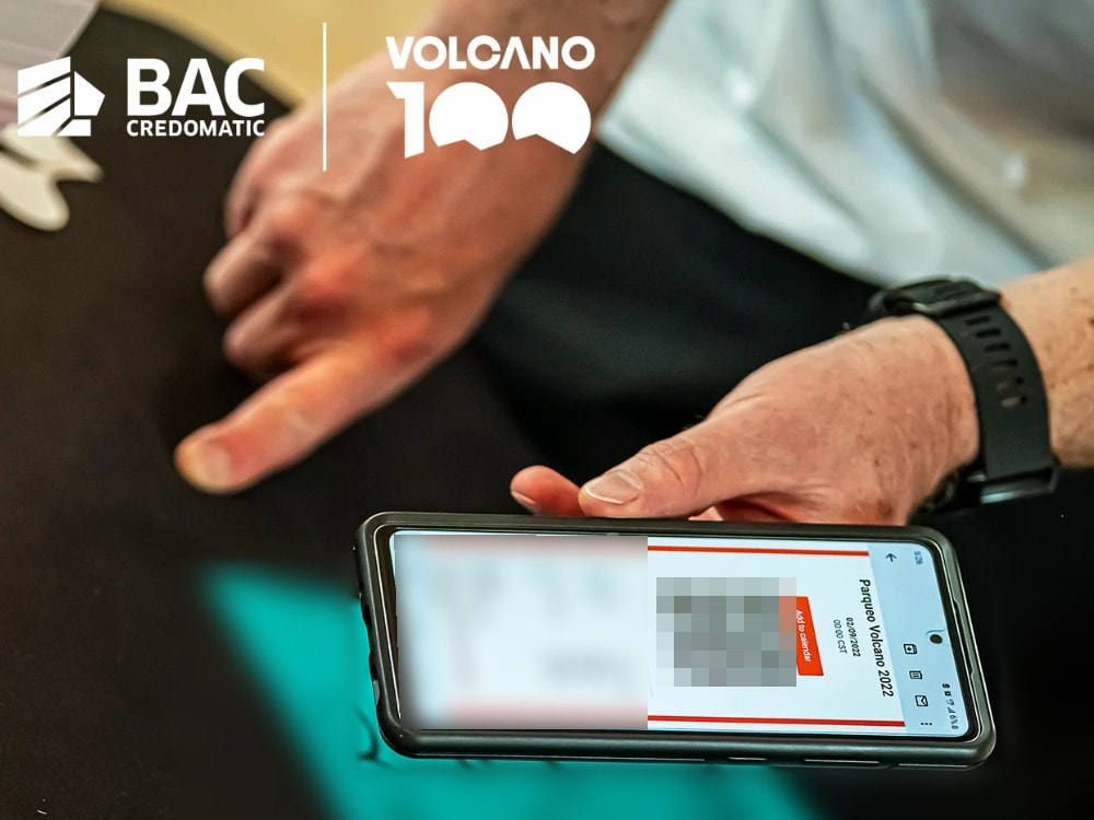 A phone showing a Volcano 2022 parking pass with its QR code blurred, held over a registration table